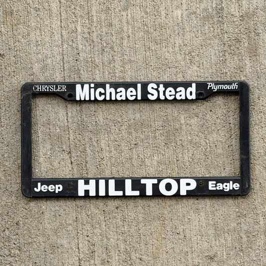Photo of a 1990 Era Michael Stead Hilltop California Dealer License Plate Frame Auto Tag Garage Decor Vintage
 Plastic Chrysler Plymouth Jeep with original patina