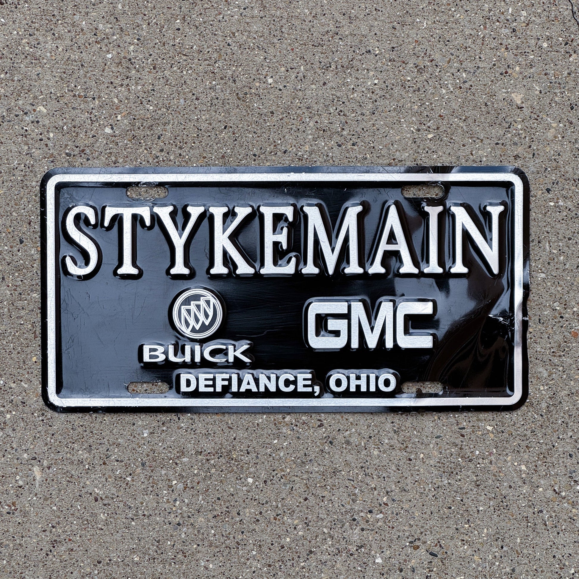 Photo of a 1990 Era Ohio Booster License Plate Auto Tag Garage Decor Vintage Buick GMC Dealer Stykeman Buick and GMC Defiance OH with original patina