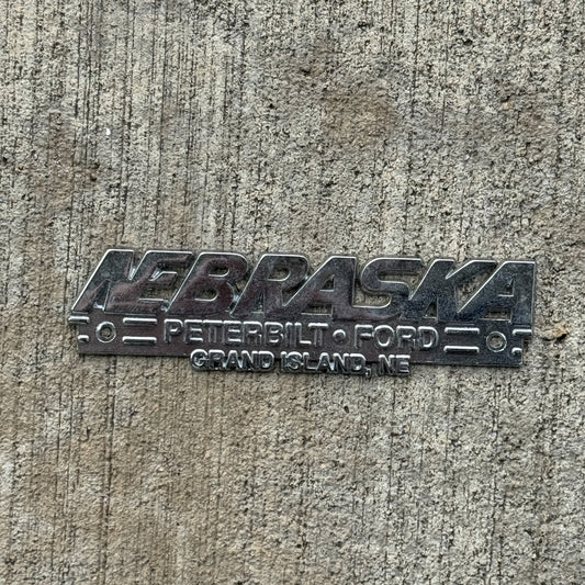 Photo of a 1990 Era Peterbilt Grand Island Nebraska Dealer Badge Emblem Auto Tag Garage Decor Vintage Ford Dealership with original patina