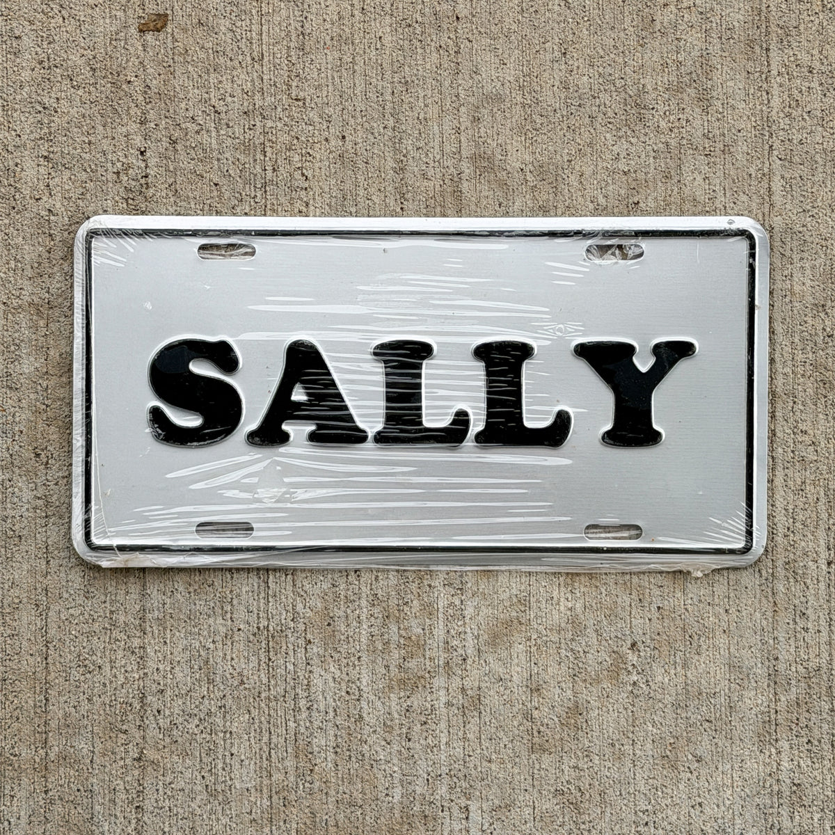 Photo of a 1990 Era SALLY Booster License Plate Auto Tag Garage Decor Vintage
 Metal NOS with original patina