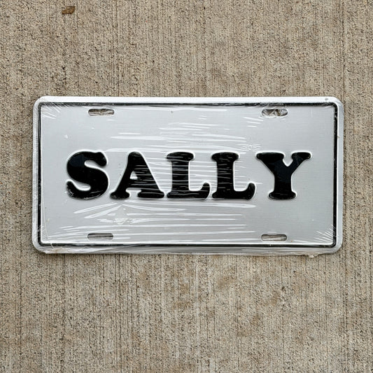 Photo of a 1990 Era SALLY Booster License Plate Auto Tag Garage Decor Vintage
 Metal NOS with original patina