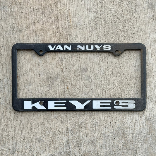 Photo of a 1990 Era Van Nuys California Dealer License Plate Frame Auto Tag Garage Decor Vintage
 Plastic Keyes European with original patina