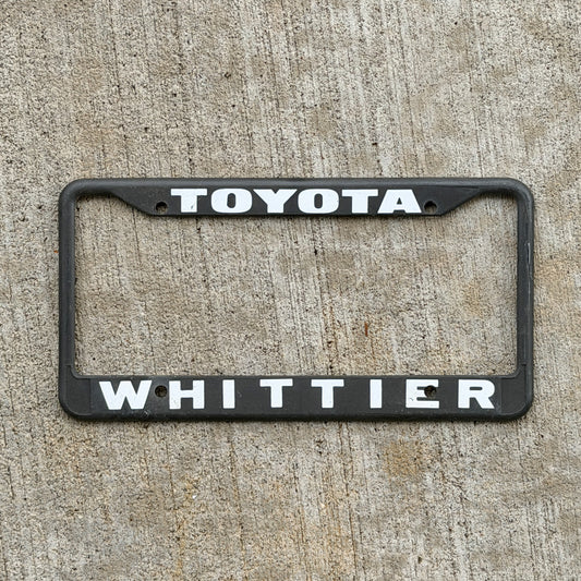 Photo of a 1990 Era Whittier California Dealer License Plate Frame Auto Tag Garage Decor Vintage
 Plastic Toyota with original patina