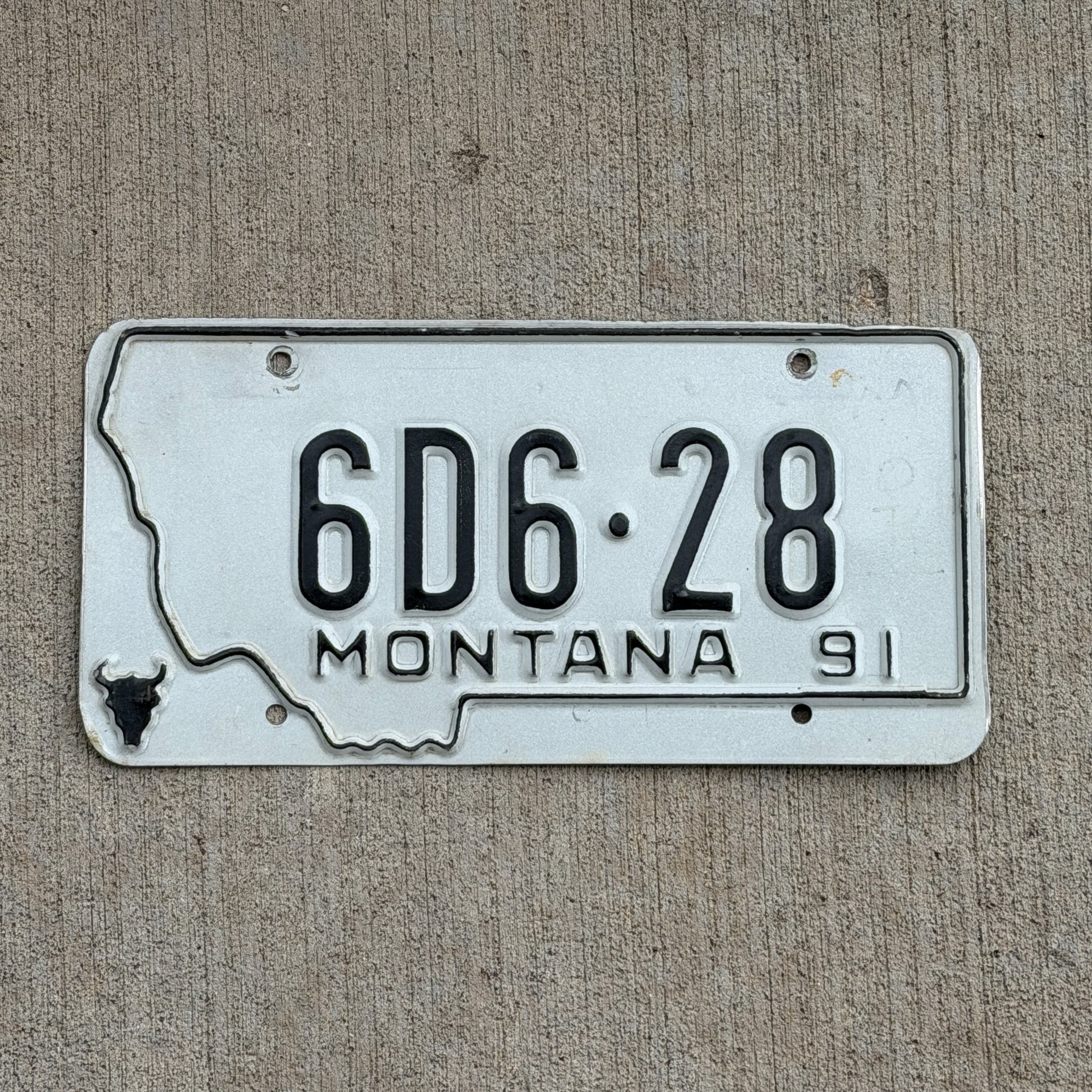 Photo of a 1991 Montana Dealer License Plate Auto Tag Garage Decor Vintage State Shape 6D6 28 with original patina