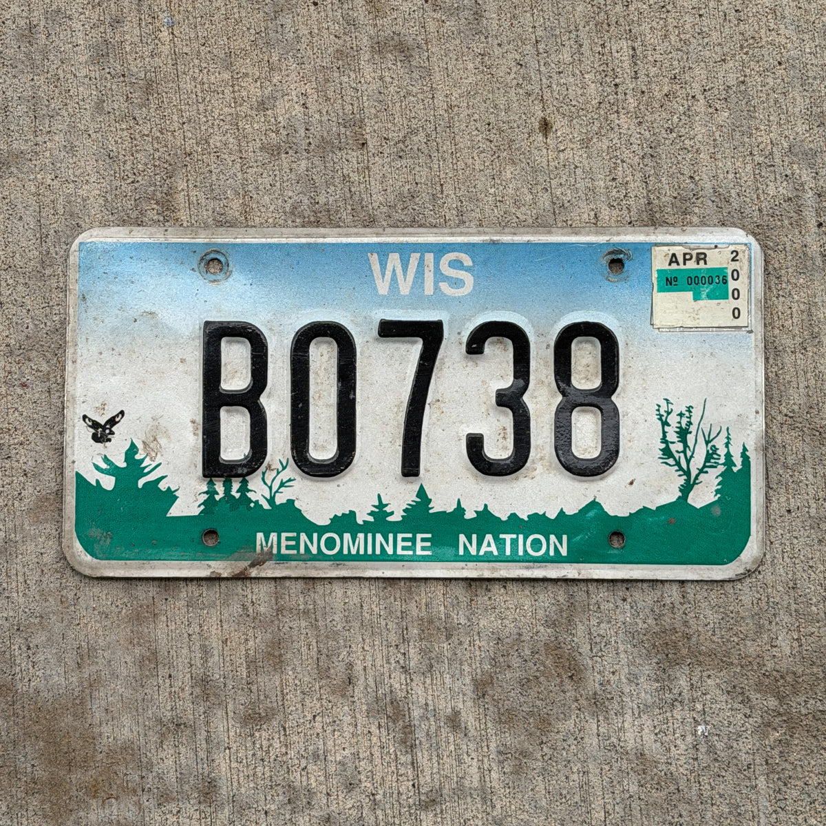 Photo of a 1994 2000 Wisconsin Graphic / Specialty License Plate Auto Tag Garage Decor Vintage Native American Indian Tribe Menominee Nation B 0738 with original patina