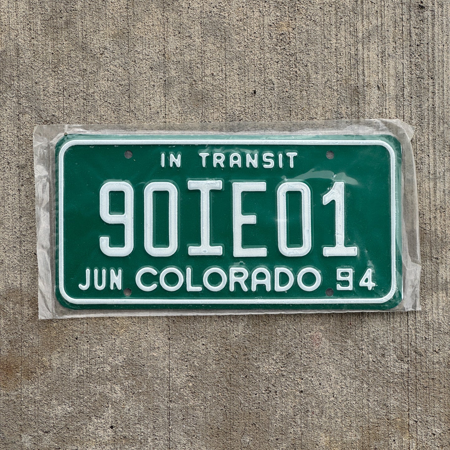Photo of a 1994 Colorado In Transit Dealer License Plate Auto Tag Garage Decor Vintage New Old Stock NOS 90 IE 01 with original patina