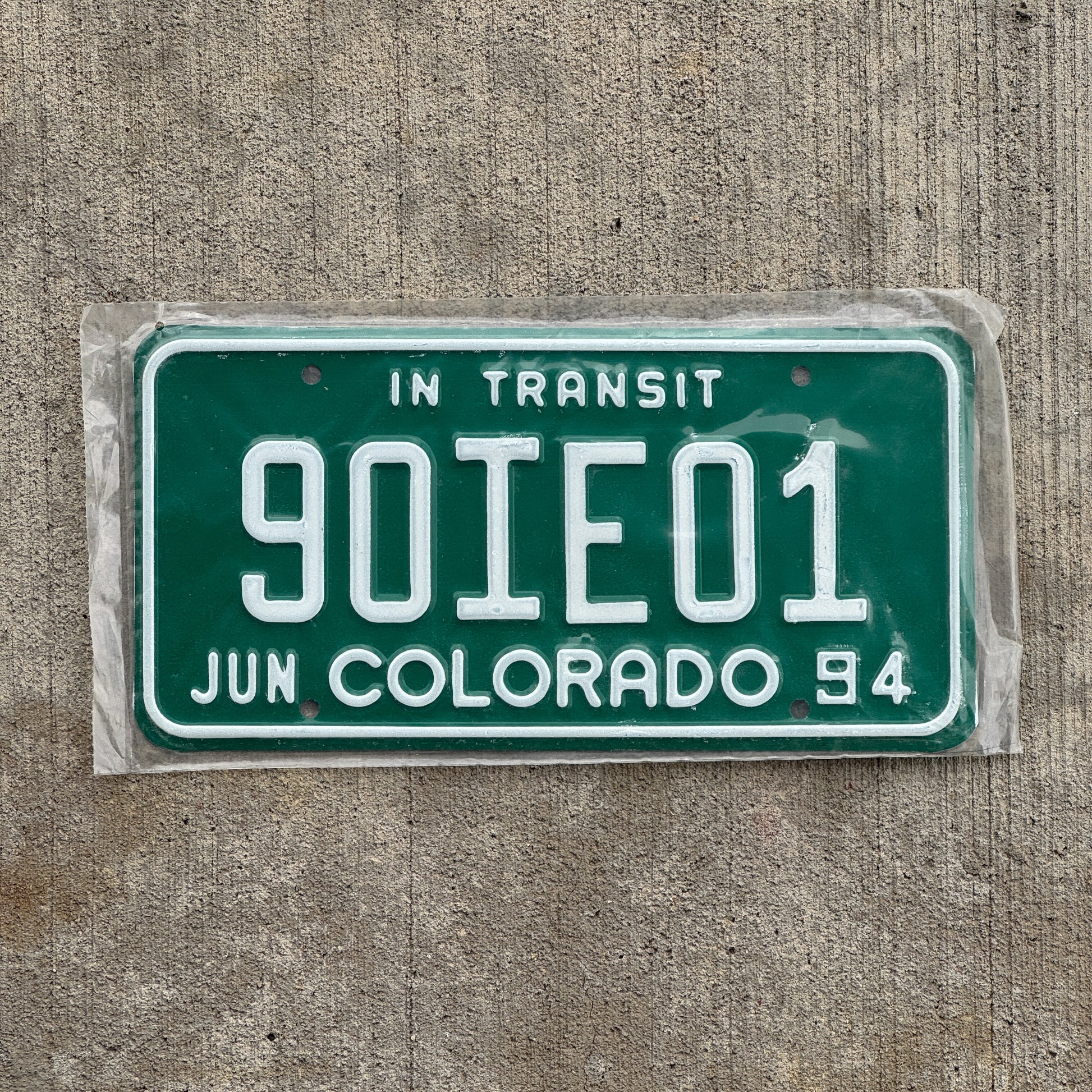 Photo of a 1994 Colorado In Transit Dealer License Plate Auto Tag Garage Decor Vintage New Old Stock NOS 90 IE 01 with original patina