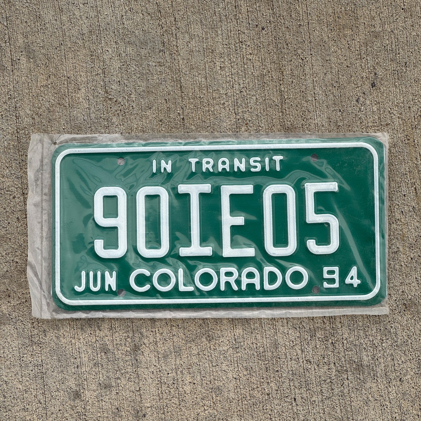 Photo of a 1994 Colorado In Transit Dealer License Plate Auto Tag Garage Decor Vintage New Old Stock NOS 90 IE 05 with original patina