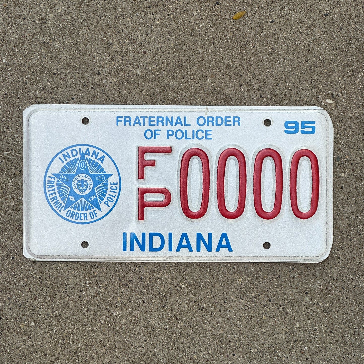 Photo of a 1995 Indiana Graphic Sample License Plate Auto Tag Garage Decor Vintage Fraternal Order of Police FP 0000 with original patina