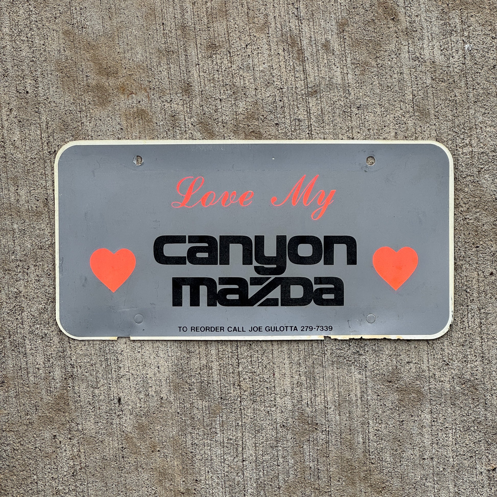 Photo of a 2000 Era Canyon Mazda Phoenix Arizona Booster License Plate Auto Tag Garage Decor Vintage Flimsy Plastic with original patina