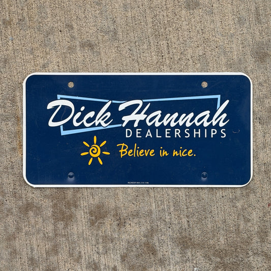 Photo of a 2000 Era Dick Hannah Dealerships Booster License Plate Auto Tag Garage Decor Vintage Plastic with original patina