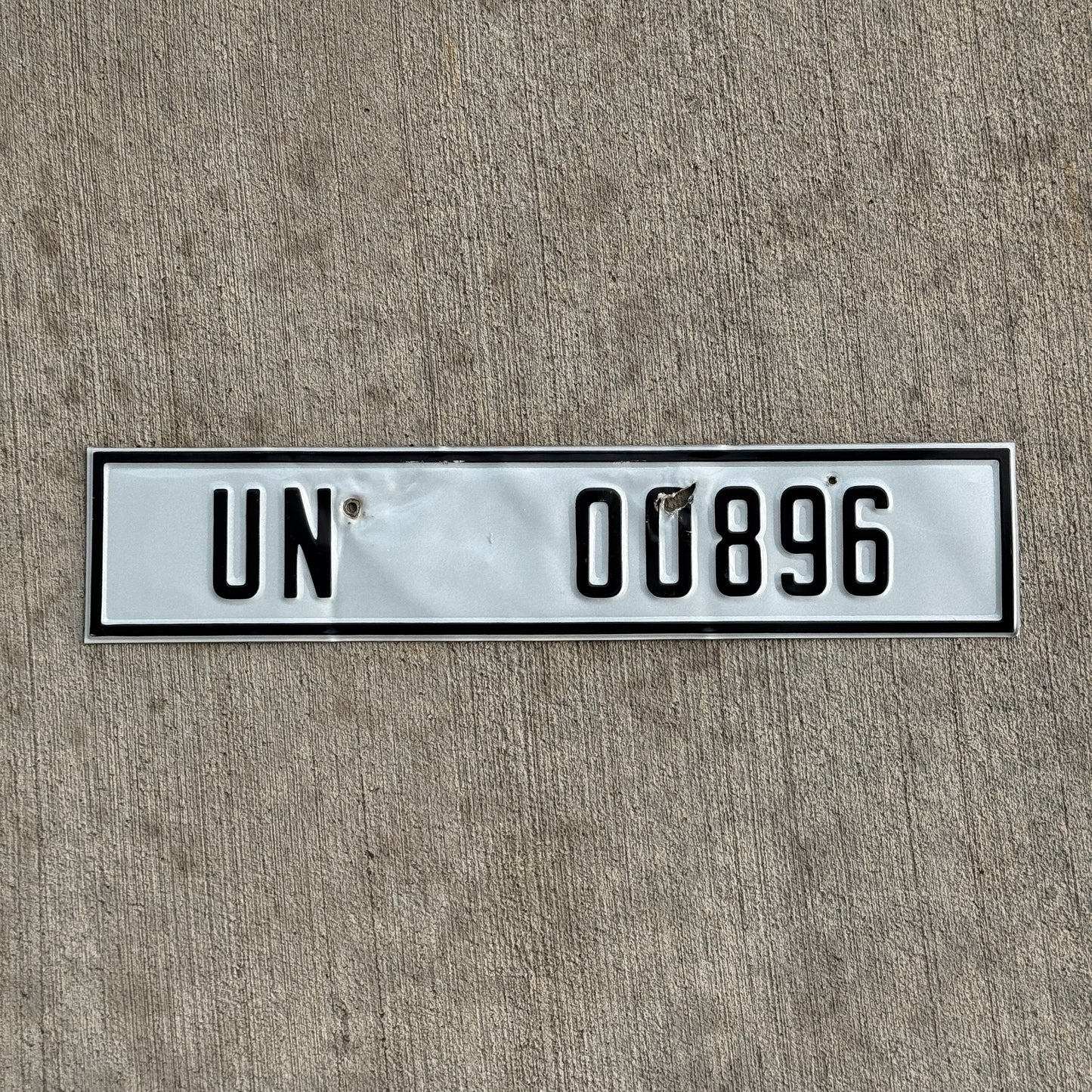 Photo of a 2000 Era United Nations License Plate Auto Tag Garage Decor Vintage UN 00896 with original patina