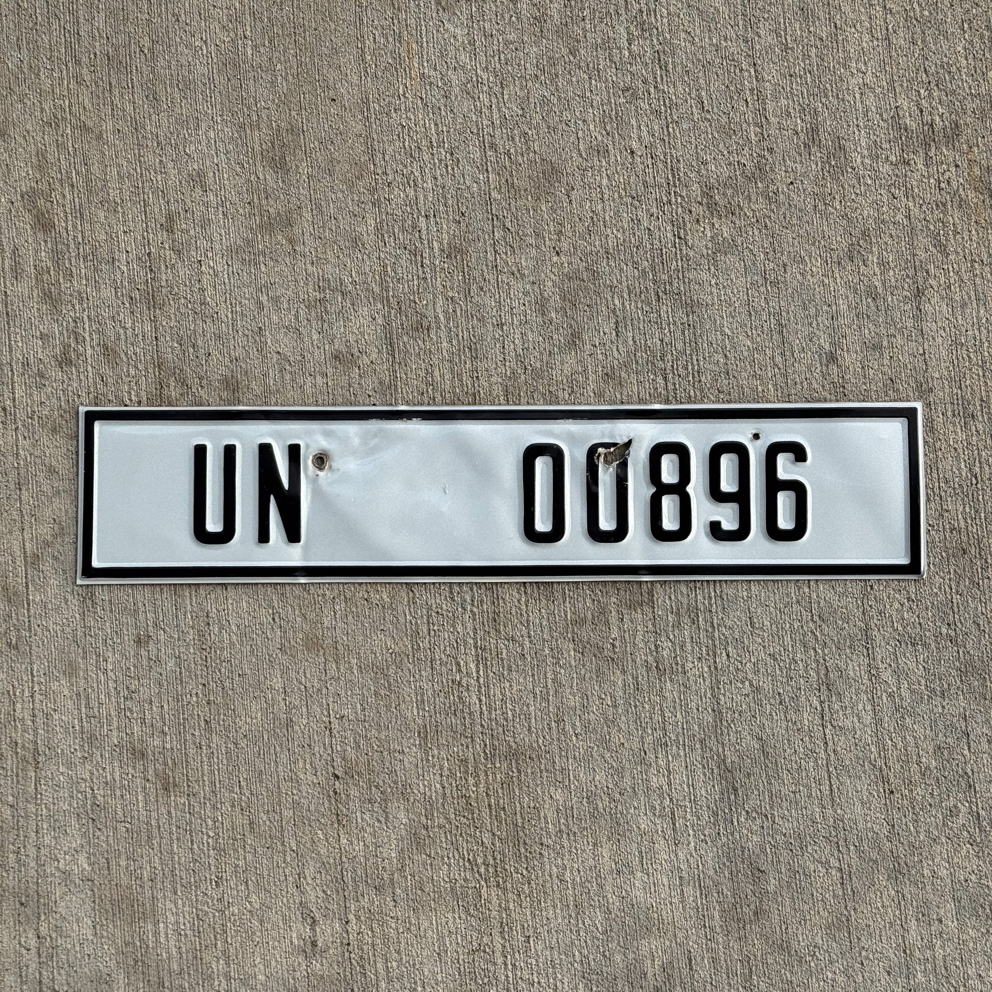Photo of a 2000 Era United Nations License Plate Auto Tag Garage Decor Vintage UN 00896 with original patina