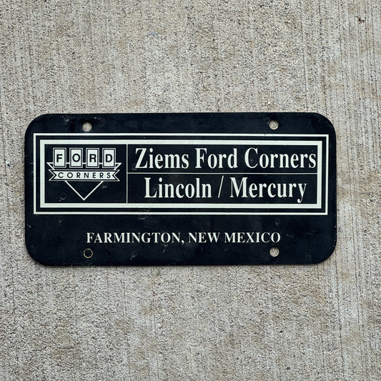 Photo of a 2000 Era Ziems Ford Corners Farmington New Mexico Booster License Plate Auto Tag Garage Decor Vintage Lincoln Mercury Flimsy Plastic with original patina