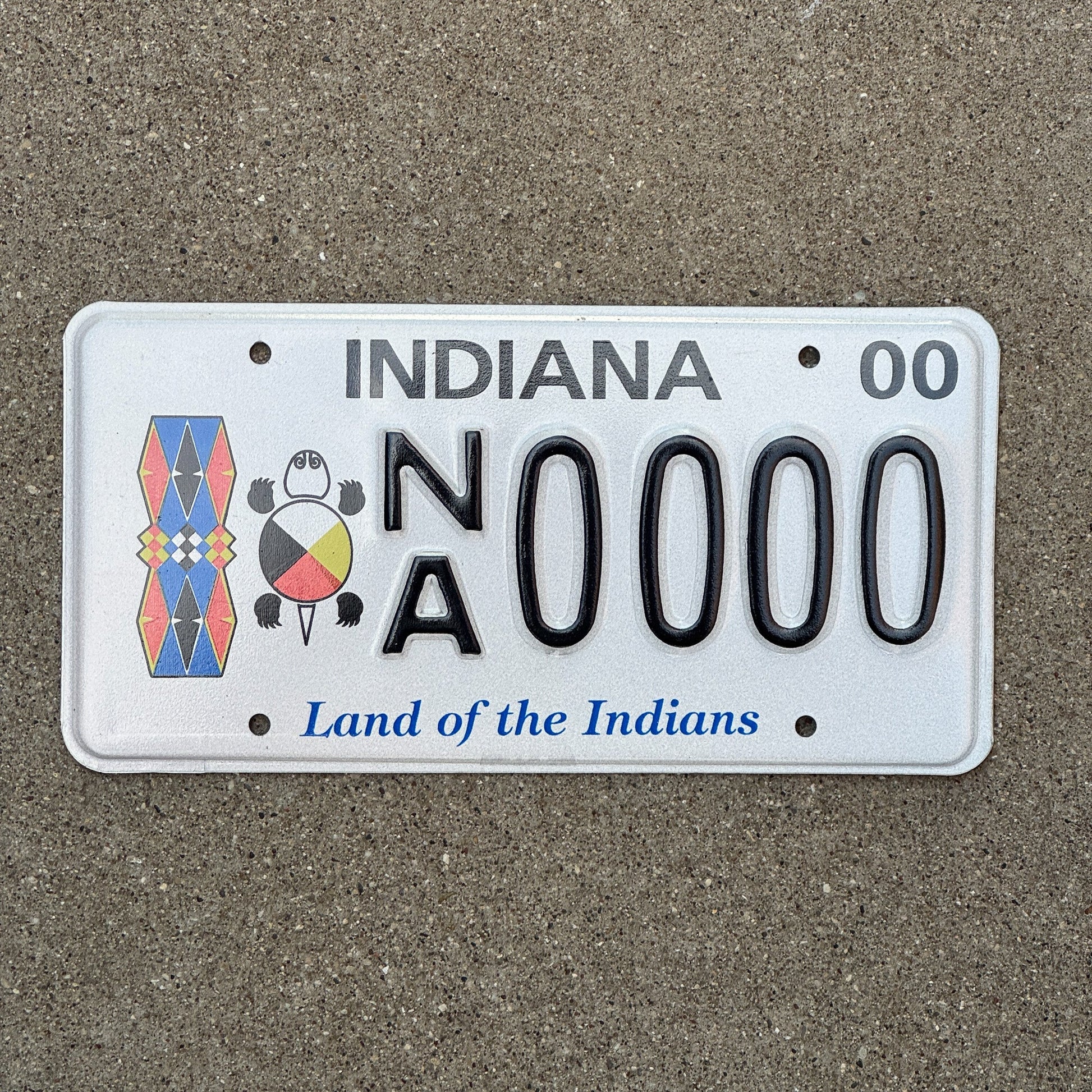 Photo of a 2000 Indiana Graphic Sample License Plate Auto Tag Garage Decor Vintage Land of The Indians Tribal NA 0000 with original patina