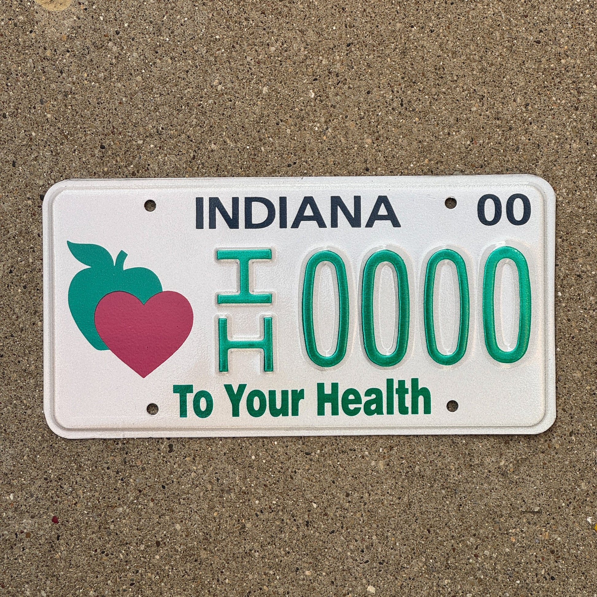 Photo of a 2000 Indiana Graphic Sample License Plate Auto Tag Garage Decor Vintage To Your Health IH 0000 with original patina