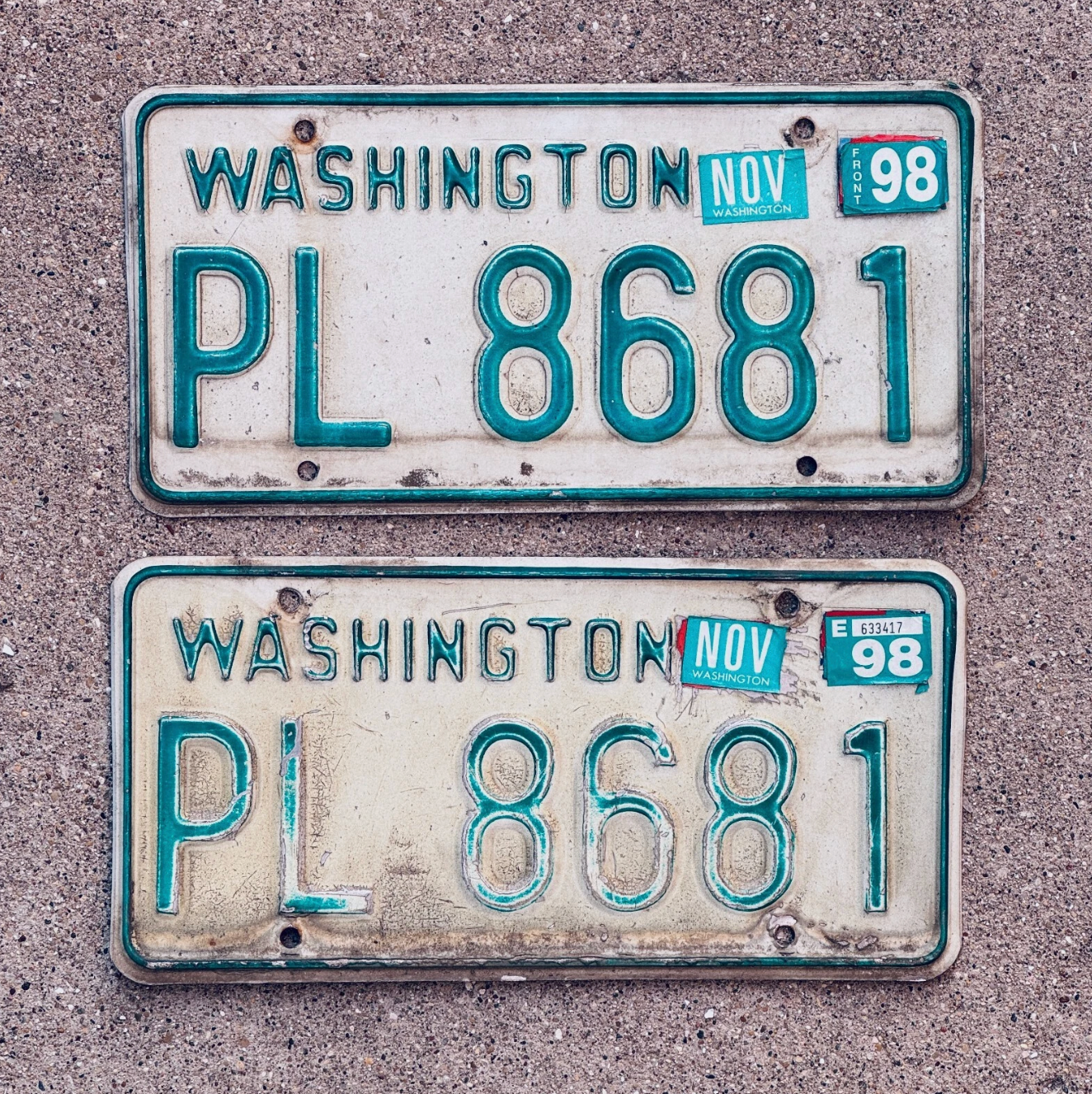 Two Washington state license plates with the number PL 8681 on a concrete surface.