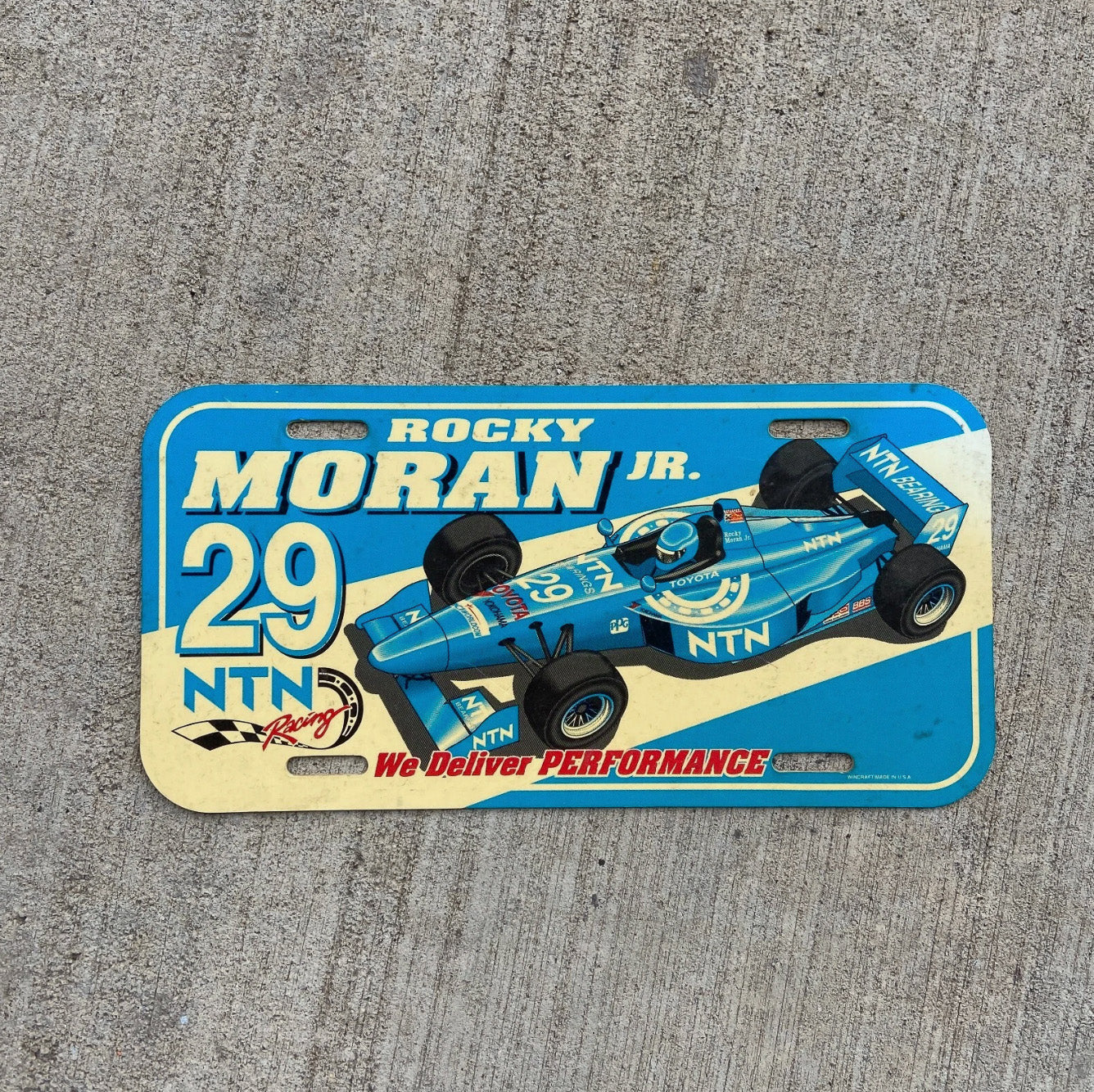 Photo of a Booster License Plate Auto Tag Garage Decor Vintage 29 Indycar NTN Plastic Rocky Moran Jr with original patina